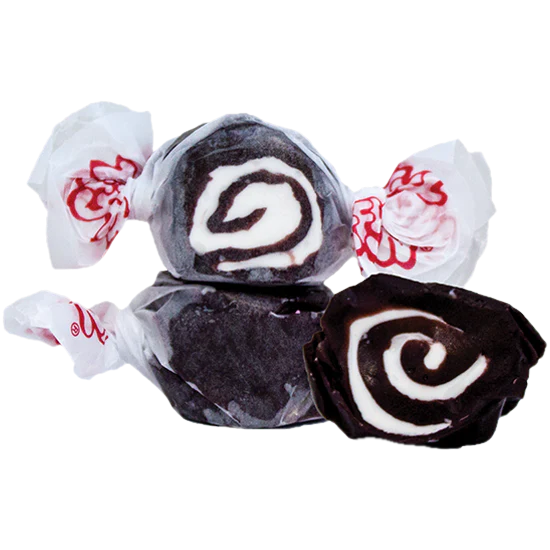 Three pieces of Black Licorice Salt Water Taffy – Freeze-Dried Classic with a Bold, Crunchy Twist, each wrapped in white wax paper with red print. One taffy is unwrapped, revealing its distinctive swirl pattern inside.