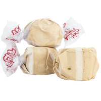 Thumbnail for Three pieces of tan and white Butterscotch Salt Water Taffy - Freeze-Dried Classic with a Buttery Sweet Crunch: two unwrapped, one partially wrapped in white wax paper with red text—a nostalgic candy treat.