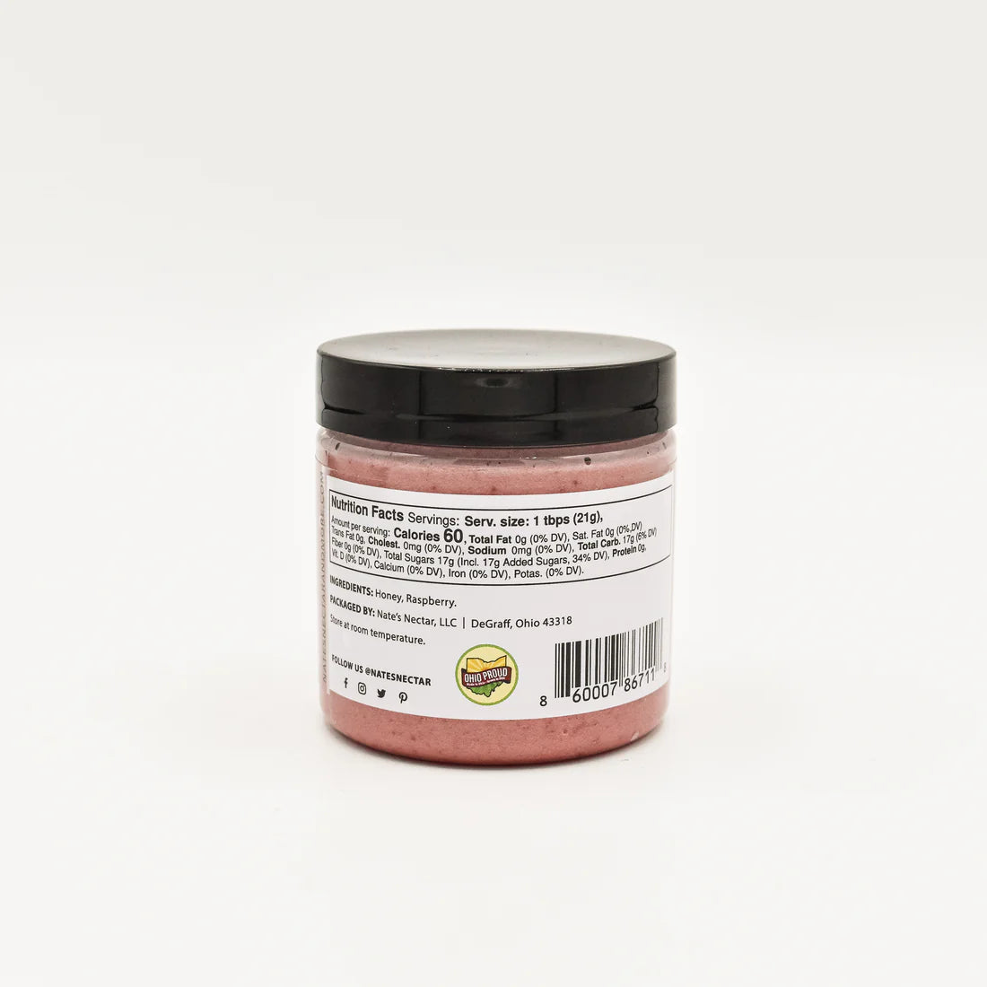 A jar with a black lid containing pink Nate’s Nectar Raspberry Creamed Honey is shown from the back. The label features nutrition facts, ingredients, a barcode, and logo, but text is too small to read. Background is plain white.