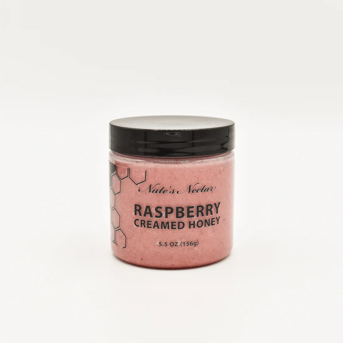 A jar of Nate’s Nectar Raspberry Creamed Honey – Tangy, Sweet & Spreadably Smooth sits against a white background, featuring a black lid, pink raspberry-infused honey inside, and a bee-themed label.