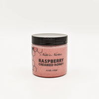 Thumbnail for A jar of Nate’s Nectar Raspberry Creamed Honey – Tangy, Sweet & Spreadably Smooth sits against a white background, featuring a black lid, pink raspberry-infused honey inside, and a bee-themed label.