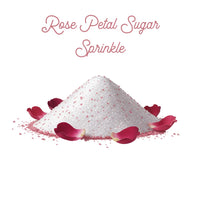 Thumbnail for A mound of floral sugar with pink specks is surrounded by scattered rose petals. Above it, 🌹 Rose Petal Sugar Sprinkle is elegantly written in cursive font.