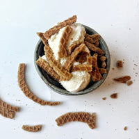 Thumbnail for A bowl of vanilla ice cream topped with Stroopwafel Just the Cookies 🧇 – 100g Bag of Sweet Snacking Bliss, with extra waffle cookie pieces scattered around the bowl on a white surface.