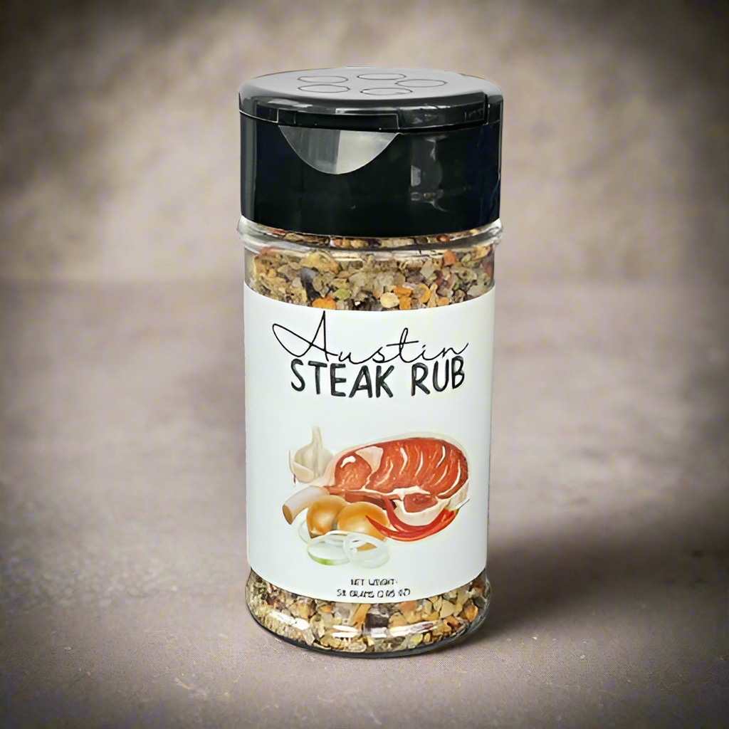 A clear plastic jar labeled Austin Steak Rub š„©, featuring images of steak, garlic, and onions, sits on a neutral surface against a light beige background.