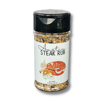 Thumbnail for A clear plastic jar labeled Austin Steak Rub š„© displays an image of steak, garlic, and onions. The coarse steak seasoning blend is visible inside, sealed with a black flip-cap lid.