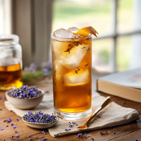 Thumbnail for The London Haze – A Soft Storm in a Teacup ☁️🫖💜 sits tall on the table, its iced black tea topped with an orange twist and lavender sprigs, alongside bowls of dried lavender and honey for a cozy, sunlit vibe.