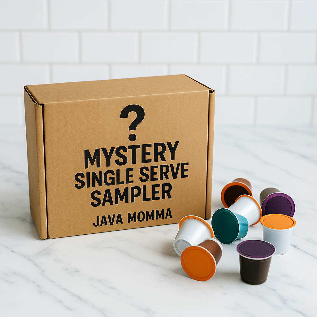 A Java Momma Mystery Single Serve Sampler box sits on a white marble countertop with a white subway tile background. A scattered assortment of colorful coffee pods surrounds the box, creating a clean and modern coffee display with a touch of mystery and fun.