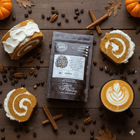 Thumbnail for Flat lay of Java Momma Oh My Gourd Becky flavored coffee bag with pumpkin roll slices topped with creamy icing, latte with foam art, cinnamon sticks, and scattered coffee beans – pumpkin roll inspired coffee scene