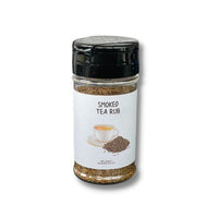 Thumbnail for A clear spice jar with a black lid labeled Smoked Tea Rub š„ displays a teacup, loose leaves, and Lapsang Souchong hints on the white label, evoking its rich, smoky flavor.