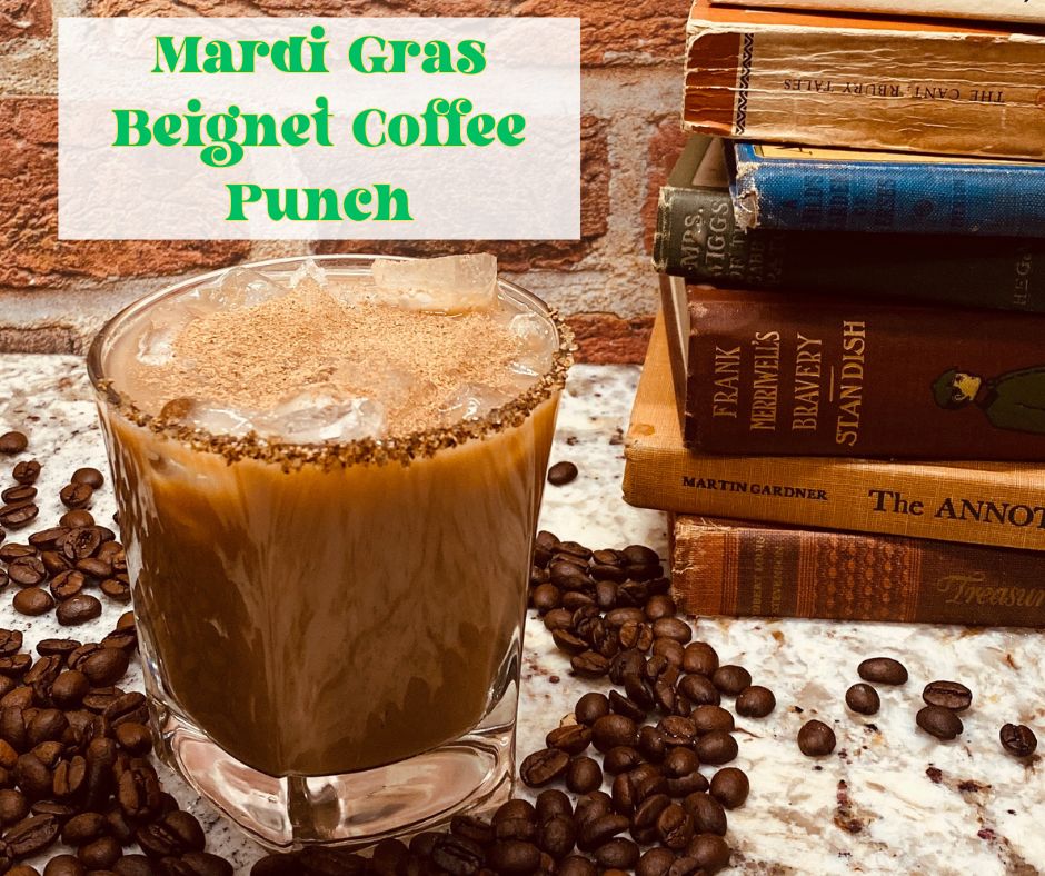 A creamy Mardi Gras Beignet Coffee Milk Punch served in a glass with ice, rimmed with cinnamon sugar, and dusted with cinnamon. Surrounded by coffee beans and stacked vintage books, set against a rustic brick background.