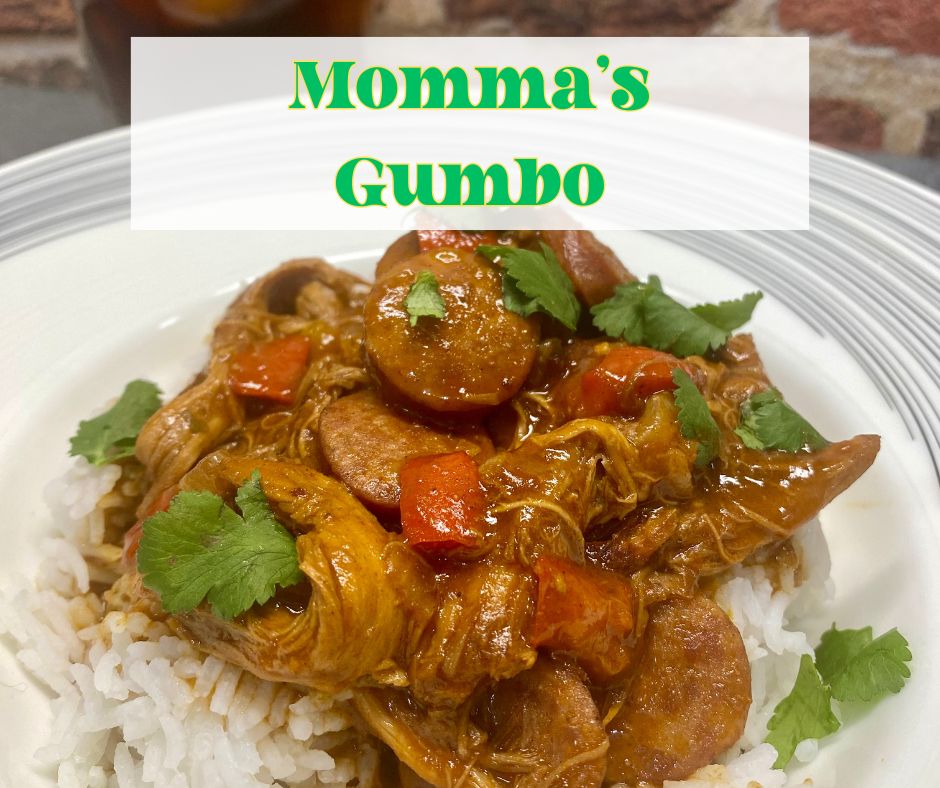 A hearty bowl of Momma’s Gumbo served over white rice, featuring shredded chicken, Andouille sausage, red bell peppers, and a rich, flavorful sauce, garnished with fresh cilantro.