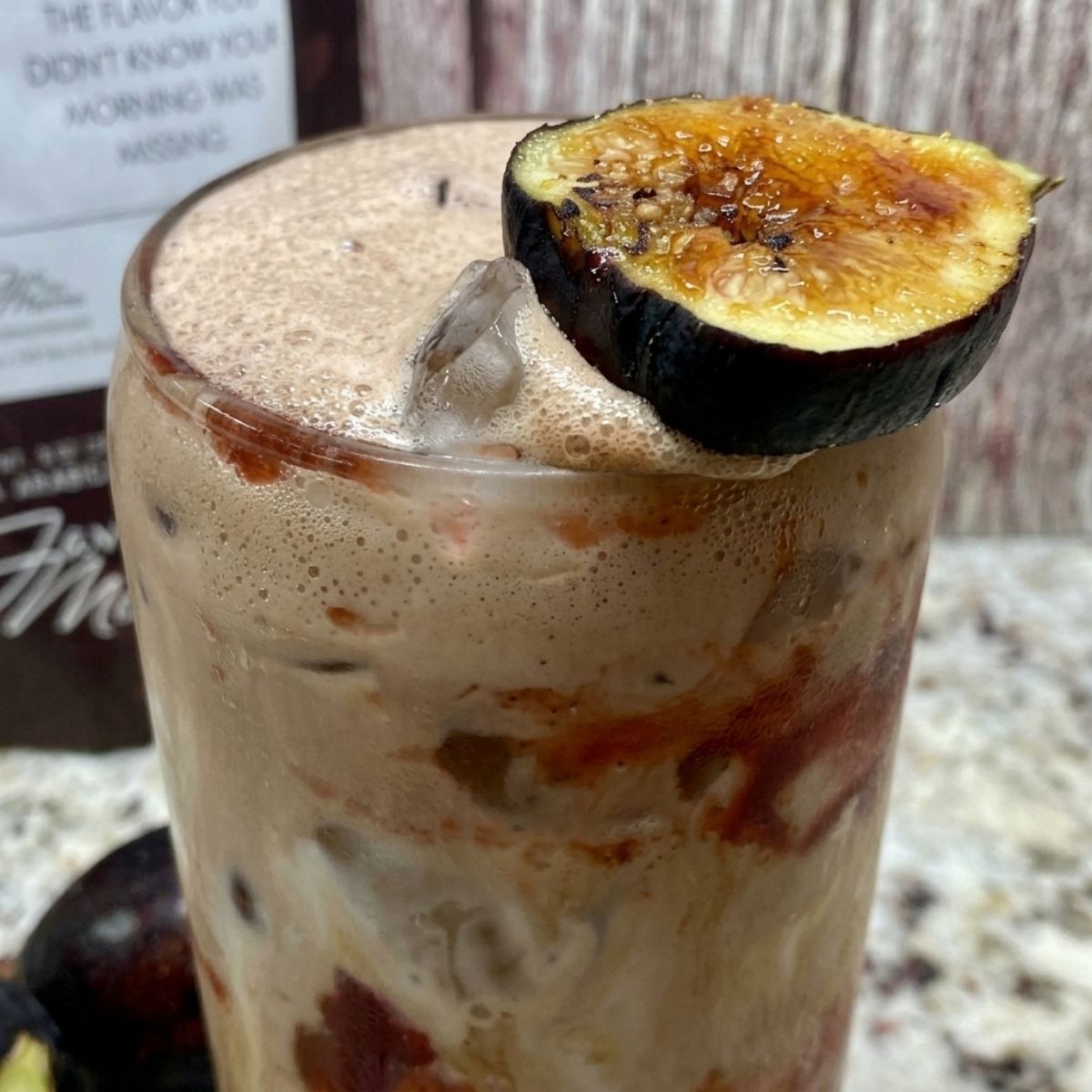 Close-up of a Chocolate Fig Latte showing fig preserves swirled through iced coffee and a frothy cold foam top