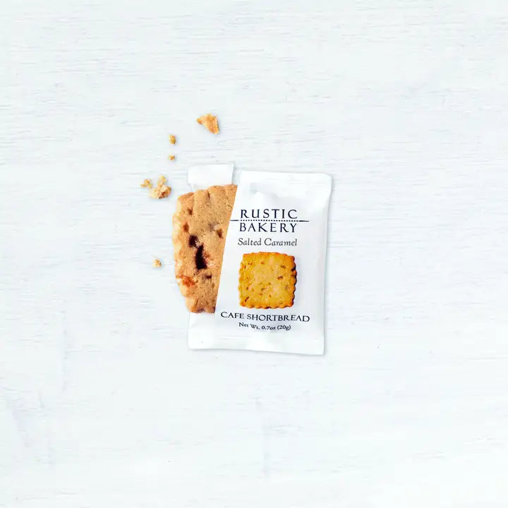 A Salted Caramel Shortbread Cookie 🧈 – Buttery, Golden & Irresistibly Simple, partially unwrapped from its white packaging, rests on a light surface with a few crumbs—an inviting single-serve cookie moment.