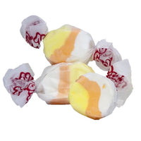 Thumbnail for Three pieces of Candy Corn Salt Water Taffy—freeze-dried for a sweet, crunchy twist—come in classic white, yellow, and orange swirls wrapped in wax paper with red writing. An irresistible Halloween treat for candy lovers!.
