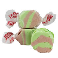 Thumbnail for Three pieces of Dirty Soda Salt Water Taffy - Freeze-Dried Creamy Cola Candy with a Crunch, featuring green and brown stripes, two stacked and one in front, are isolated on a white background.