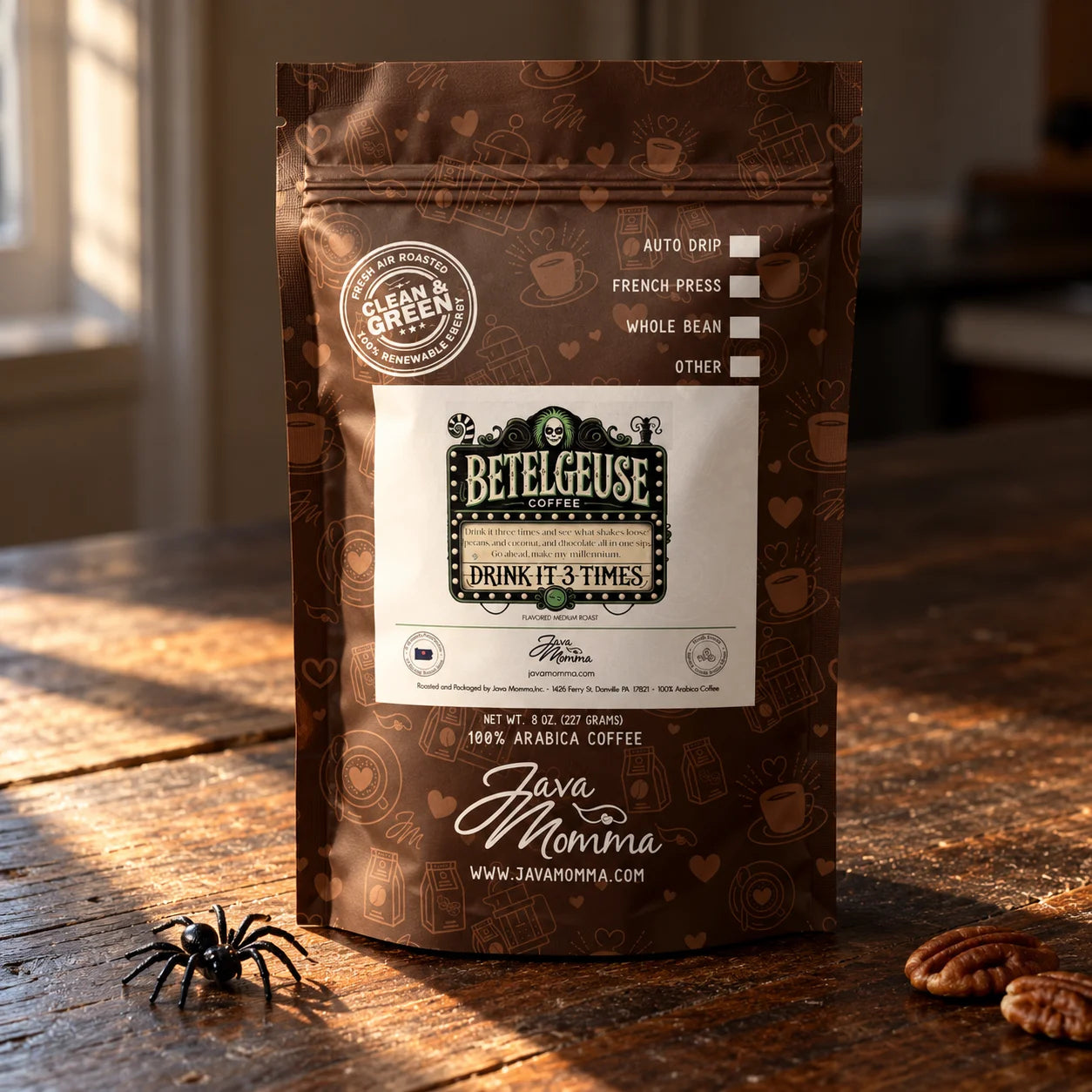A stand-up pouch of Betelgeuse Java Momma coffee on a rustic wooden table, with warm sunlight and shadows, a small toy spider at the bottom left, and pecans at the bottom right.