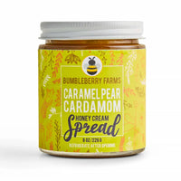 Thumbnail for A jar of Bumbleberry Farms Caramel Pear Cardamom Honey Cream Spread on a white background. The jar has a white lid and a yellow label with illustrations of a bee and botanical patterns.