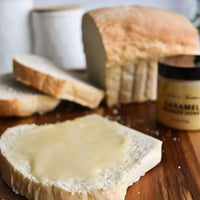 Thumbnail for A slice of white bread with Nate’s Nectar Caramel Creamed Honey 🍯 is on a wooden board, with extra bread slices, a loaf, and a jar of Nate’s Nectar Caramel Creamed Honey in the background.