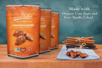 Thumbnail for Three bags of Nuts on the Run Cinnamon Almonds pure vanilla extract are displayed on a wooden table next to loose cinnamon sticks and vanilla beans on a blue cloth, with text reading 'Made with Organic Cane Sugar and Pure Vanilla Extract.'.