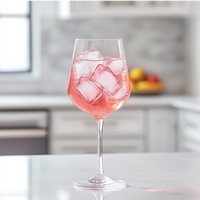 Thumbnail for A stemmed glass with a pink drink and ice, made using Dragon Fruit Acai Skinny Syrup – Fruity, Flirty & Island-Ready 🐉🍇🌺, sits on a white countertop in a modern kitchen with a blurred fruit bowl in the background.