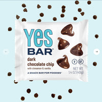 Thumbnail for A Dark Chocolate Chip YES Bar® – Like a Cookie, But Better (and Guilt-Free!) is displayed in its wrapper with chocolate chips around it on a light blue background. The packaging highlights that its gluten-free, vegan, plant-based, and contains cinnamon and vanilla.