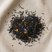 Thumbnail for Loose leaf Earl Grey tea blend with black tea, blue cornflower petals, and citrus pieces on neutral linen background.
