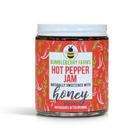 Thumbnail for A glass jar of Bumbleberry Farms Hot Pepper Jam with a white lid and a red label featuring chili pepper illustrations, set against a plain white background.