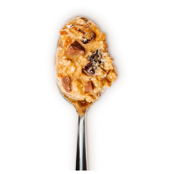 A close-up of a spoonful of Milk Chocolate Cherry Peanut Butter 🍒—featuring visible chocolate chips, raisins, and honey roasted peanuts—set against a black background. Fruity, chocolatey, and sinfully smooth.
