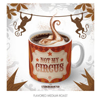 Thumbnail for A bold, circus-themed coffee mug filled with steaming hot coffee, topped with a swirl of cinnamon and sweet icing. Playful monkey silhouettes swing on a vine in the background, adding to the whimsical, rebellious vibe. The mug features a vintage-style label reading ‘Not My Circus,’ part of the Underground coffee line—brews with an extra shot of sass. Warm tones and spice accents highlight the rich, flavored medium roast inside.
