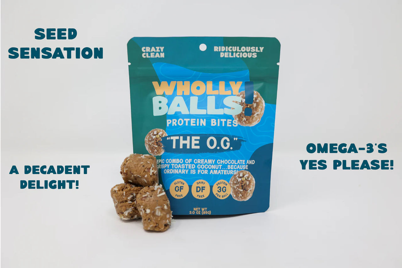 A bag of The O.G. – Chocolate Coconut Wholly Balls | Plant-Based Protein Snack stands upright, surrounded by protein bites. Bold text highlights: Seed Sensation, A Decadent Delight!, Plant-Based Protein, and Gluten-Free Goodness!.