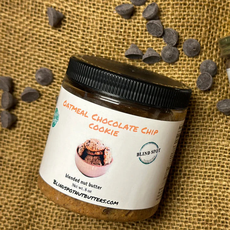 Two jars of oatmeal chocolate chip cookie butter with chocolate chips on a burlap background.