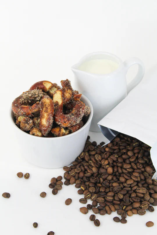 A white bowl of Coffee + Cream Pretzel Bites – Sweet, Salty, and Seriously Addictive ☕✨ sits beside spilled coffee beans and a milk pitcher, making the perfect small batch snack for coffee lovers.