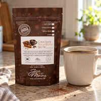 Thumbnail for A bag of Java Momma Chocolate Peanut Butter Silk Pie coffee beans stands on a countertop next to a ceramic mug, with a softly blurred kitchen background.