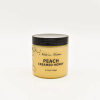 Thumbnail for A 5.5 oz jar of Nate’s Nectar Peach 🍑 Creamed Honey – Juicy, Sweet & Perfectly Spreadable; comes with a black lid and features black text with a honeycomb design on a plain white label.