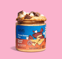 Thumbnail for A jar of 🍫 Bnutty Peanut Butter Cup – Chocolatey, Creamy, and Candy-Bar Good, topped with white and milk chocolate chips plus peanut butter cup pieces, displayed against a pink background.
