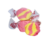 Thumbnail for Three pieces of Strawberry Banana Salt Water Taffy – Freeze-Dried Fruity Candy with a Creamy Crunch offer a tasty, colorful treat featuring pink and yellow swirls, each wrapped in white wax paper with red designs on a white background.