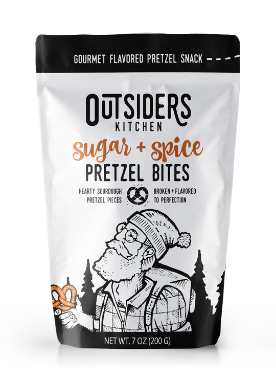 A 7 oz (200 g) bag of Sugar + Spice Pretzel Bites – Sweet, Salty, and Straight-Up Craveable 🍬🔥, crafted in small batches, with a black-and-white illustration of a bearded man in outdoor gear holding a pretzel amid trees and mountains.