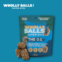 Thumbnail for A teal pouch of The O.G. – Chocolate Coconut Wholly Balls | Plant-Based Protein Snack stands upright, with several gluten-free chocolate coconut bites stacked in front against a blue background.