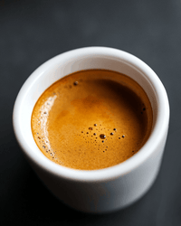 Thumbnail for Close-up of a freshly pulled espresso shot in a white ceramic cup with rich amber crema on a dark background