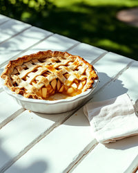 Thumbnail for Apple pie with a slice missing on a white wooden surface outdoors