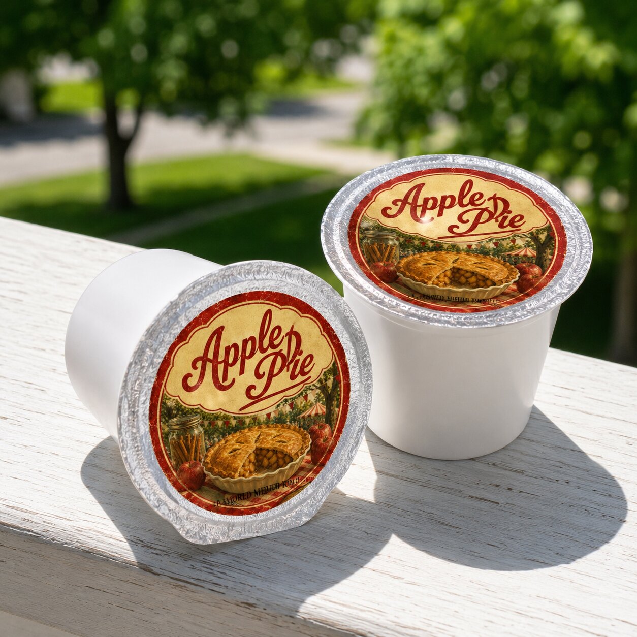 Two apple pie-flavored single serve coffee pods on a wooden surface with greenery in the background
