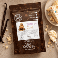 Thumbnail for A bag of Java Momma 'Birthday Cake' coffee beans is displayed on a textured beige stone surface, styled with vanilla beans, crumbs, and a slice of cake on a plate.