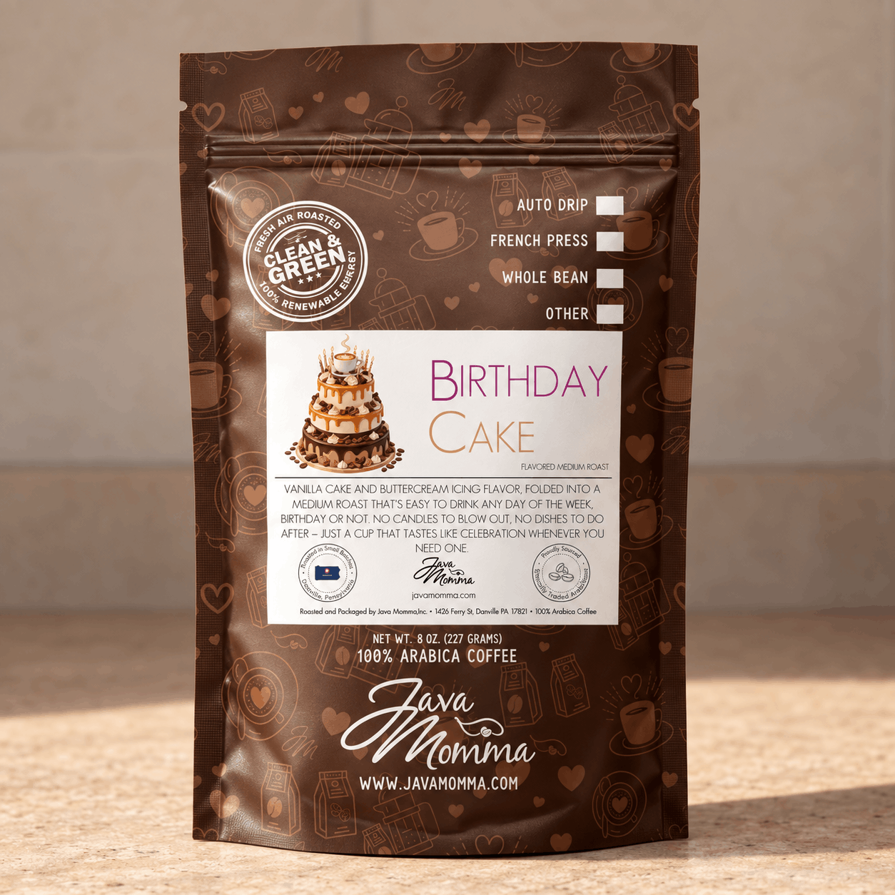 A stand-up pouch of Java Momma Coffee's 'Birthday Cake' flavored medium roast whole bean coffee, featuring a brown packaging design with cake illustrations and a white label, set against a neutral beige background.