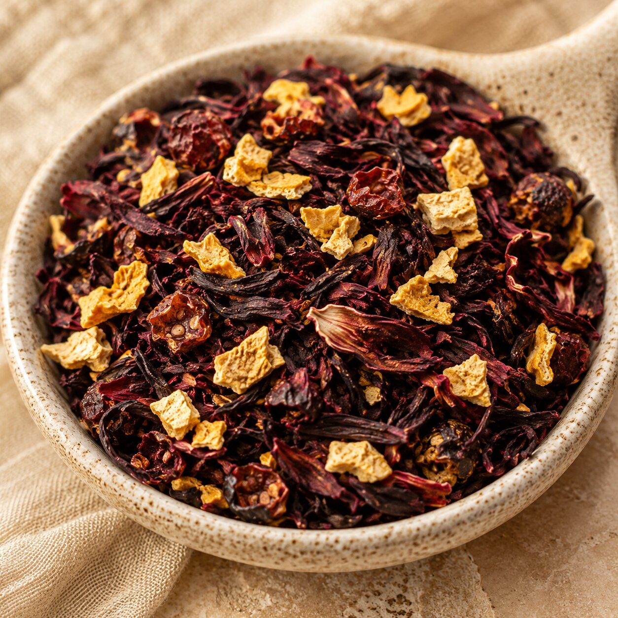 Blood Orange Moon Tea leaves with orange peel pieces in a ceramic bowl on a beige background