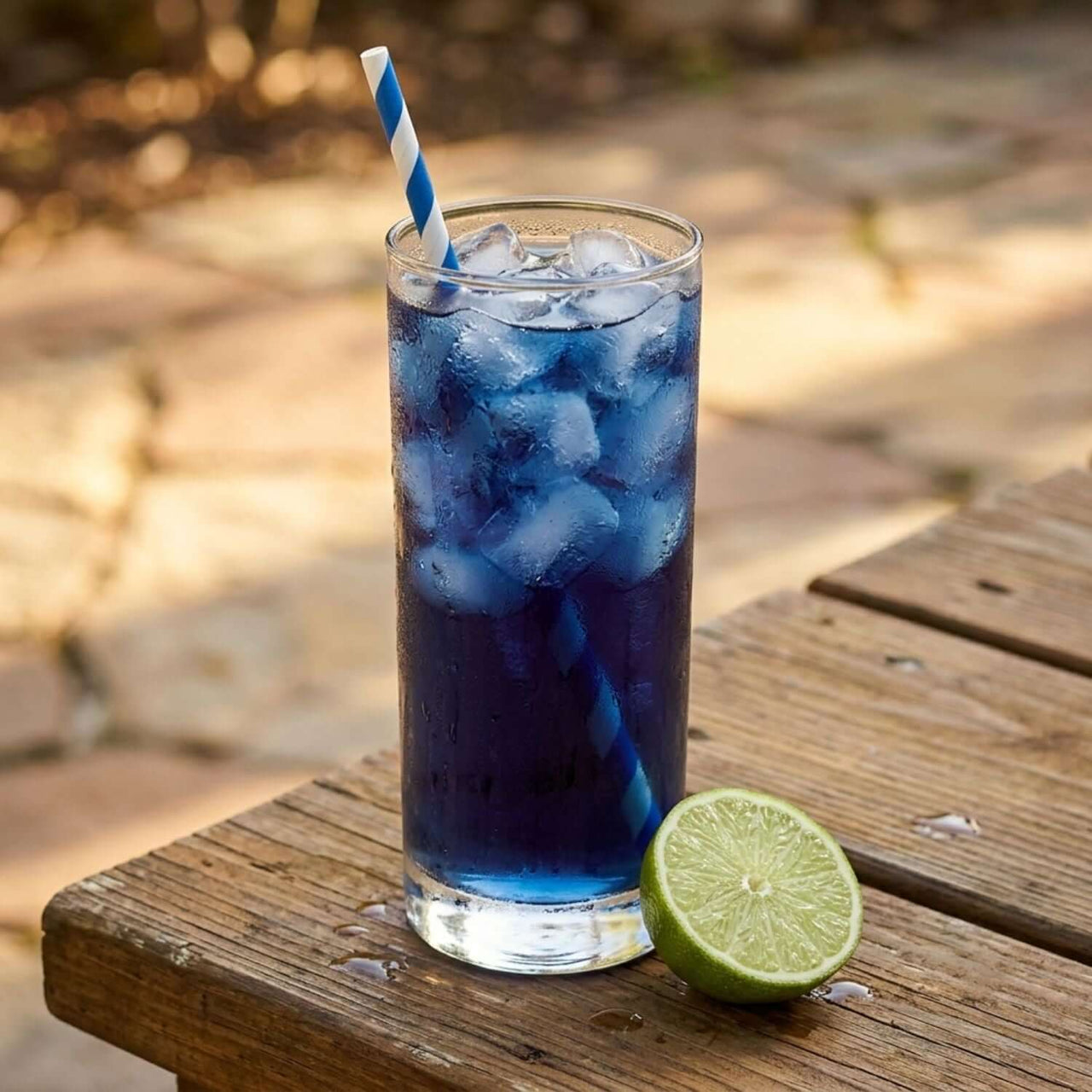 Blue Tide Cold Brew Tea Pods in a glass with ice and a lime on a wooden table.