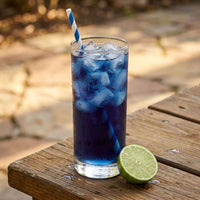Thumbnail for Blue Tide Cold Brew Tea Pods in a glass with ice and a lime on a wooden table.