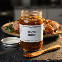 Thumbnail for Jar of Bourbon Apricot Butter with a label, wooden spoon, and plate of food in the background.