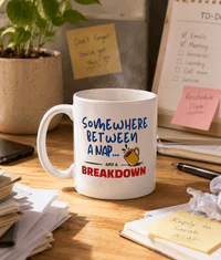 Thumbnail for Mug with humorous text on a desk with office items - Somewhere between a nap and a breakdown