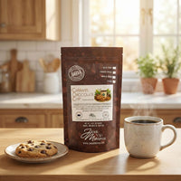 Thumbnail for Caramel Chocolate Chip Cookie coffee bag on a kitchen counter with a steaming mug and cookie nearby