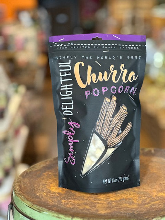 Delightful Churro Popcorn packaging on a wooden surface with a blurred background